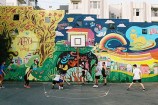 People playing basketball in front of a colourful mural.