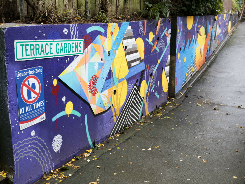 A retaiing wall painted purple with coloured patterns on top.