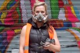 Close up of artist with paint cans and mask. 