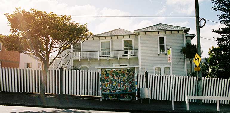 In situ: Bus shelter with bright-coloured geometric shapes in front of house.