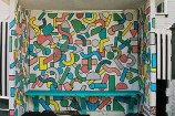 Bus shelter covered in bright-coloured geometric shapes.