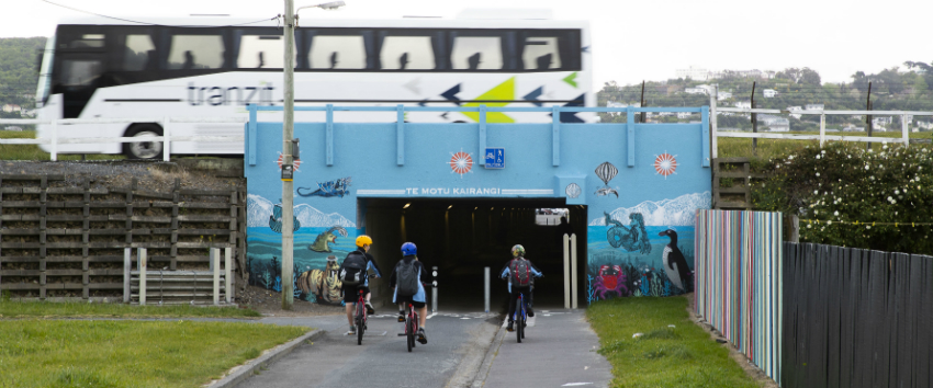 Three kids riding their bikes into the subway tunnel.