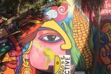 People seated in front of a Latin Collective mural in Riddiford Street, Newtown.