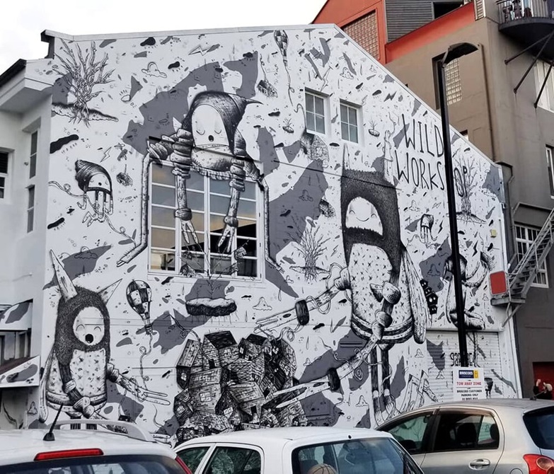 The side of a building with a black and white mural of fantasy characters.