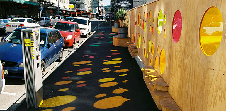 Colourful red and yellow perspex circular 'windows' set in plywood hoarding.