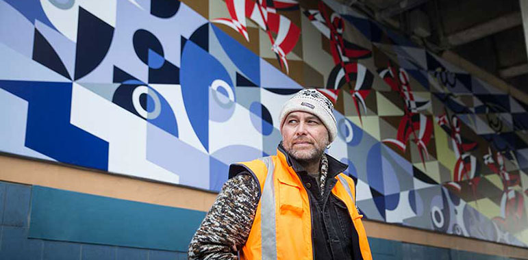 Wharehoka Smith in front of his mural.