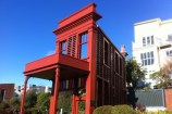 A red house facade surrounded by gardens.