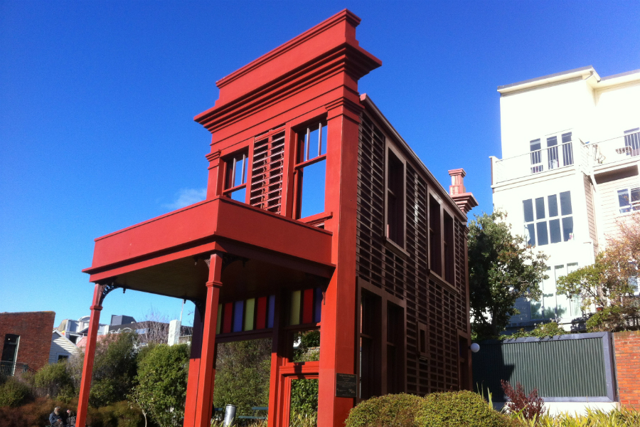 A red house facade surrounded by gardens.