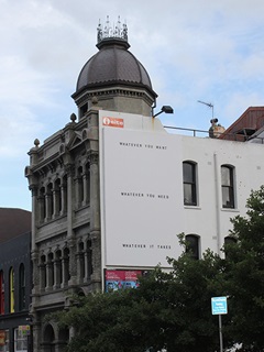 Billboard showing Whatever you want work on a building on Vivian street above Cuba Street.