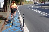 A person on a bike in the Aro Valley. One of the blue niho taniwha designs that marks Waimāpihi Awa can be seen on the uphill bike lane they are riding on.