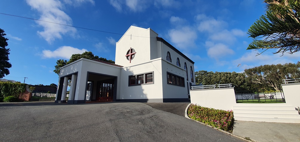 A large white chapel with a red cross at the front.