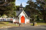 A wooden building with a turret and a red door.