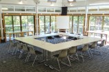 Seminar room with tables and chairs surrounded by windows.