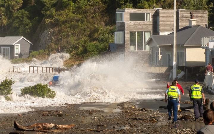 A large wave crashes onto the shore at Ōwhiro Bay.