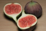 Two figs on a table, one sliced in half showing the inside.