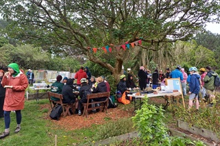 A group of people sitting at tables outdoors at the Miramar Prison Garden.