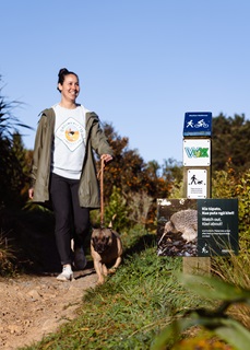 Woman walking a dog on a leash through a walkway