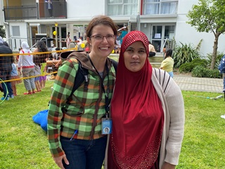 Senior Advisor Community Development Jamie Shackleton with a tenant from Newtown Apartments, with people having fun in the background.