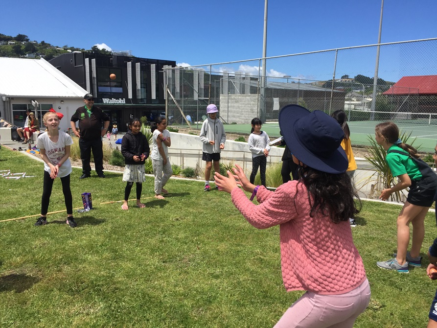 Children throwing eggs to each other as part of the egg races, with Waitohi building in the background.