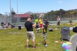 A man and a young kid practicing their boxing moves in gloves on the grass outside Waitohi.