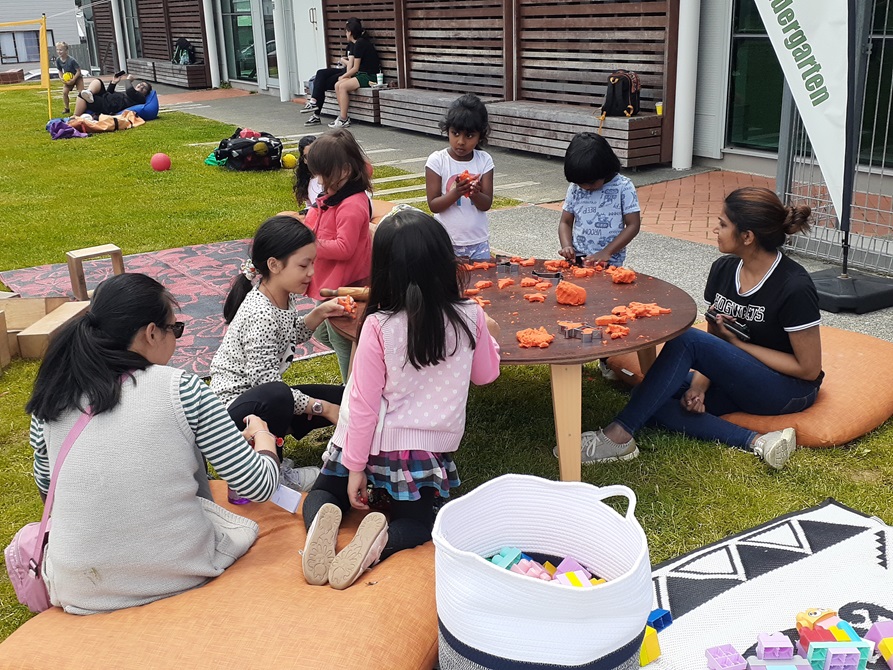 A table of children playing with playdough at a low table.