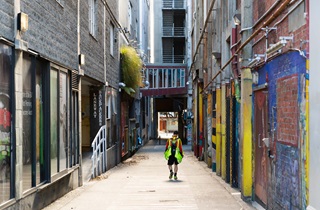 A lone postie walks down an empty Wellington laneway. 