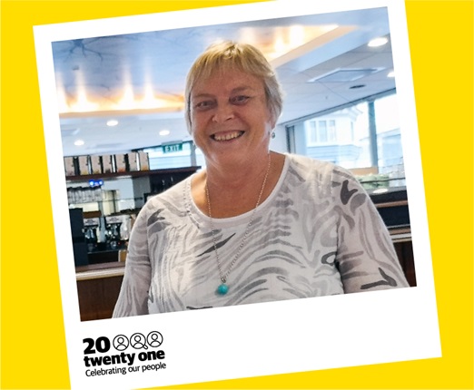 Julie Sleep smiling in a white top with a cafe behind her, pictured in a polaroid with the words 20 Twenty One: Celebrating our people.