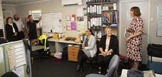 An office with five colleagues sitting and standing around the room.