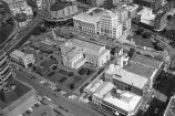 A black and white film photograph of a birds eye view of Wellington's Civic Square area in 1987, featuring the original city library, Town Hall, and lots of car parks.