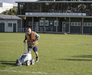 Dave Jackson uses a line marker to paint white lines on the field at Miramar's Polo Ground.