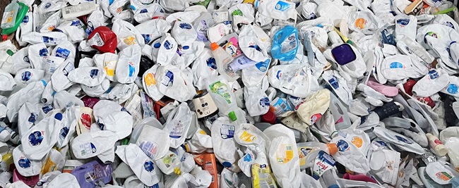 A photo of a big pile of milk bottles at a recycling plant.