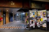 Standing noticeboards coverd in old flyers and posters stand in front of the hallway leading to the bathrooms inside the Central Library.