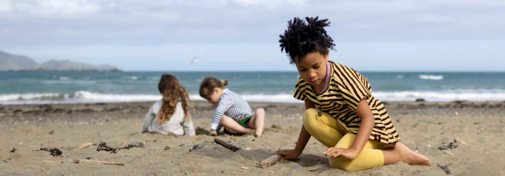 Three children playing in the sand on Lyall Bay beach.