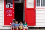 Four children sitting in the doorway of Maranui cafe in Lyall Bay.