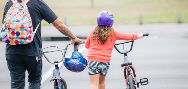 Landscape image of young child with adult pushing bikes
