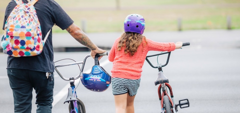 Landscape image of young child with adult pushing bikes