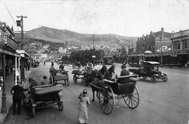 A black and white photo of Courtenay Place in 1910 with horse and carts riding beside early motorcars.