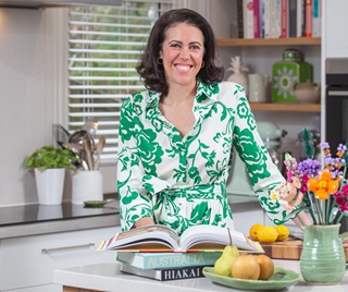 Sarah Meikle standing in a kitchen with a cookbook.