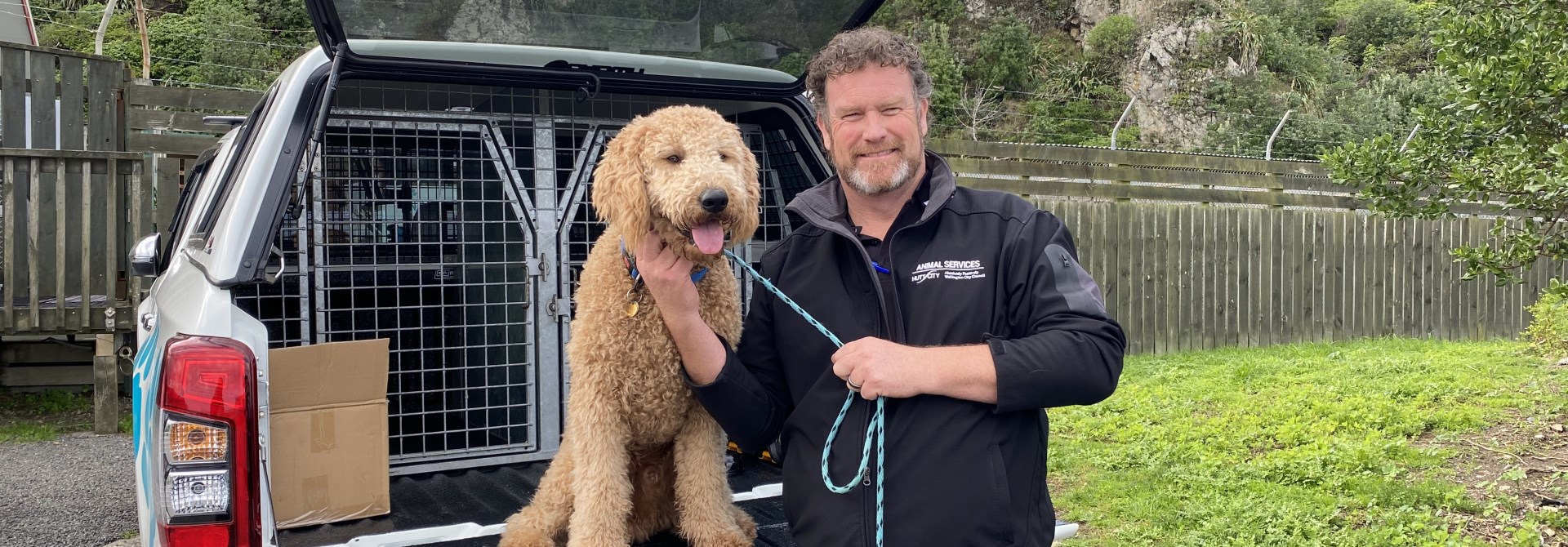 Man standing infront of a car with a dog.