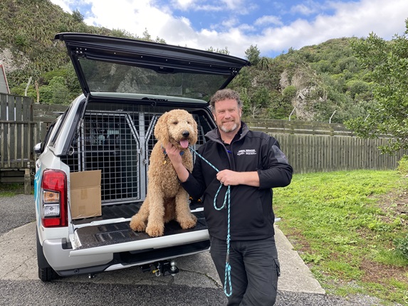 Man standing infront of a car with a dog.