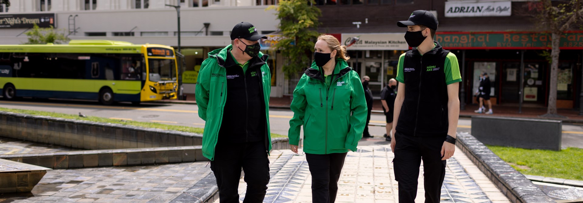 Three people walking across Te Aro park in Wellington.