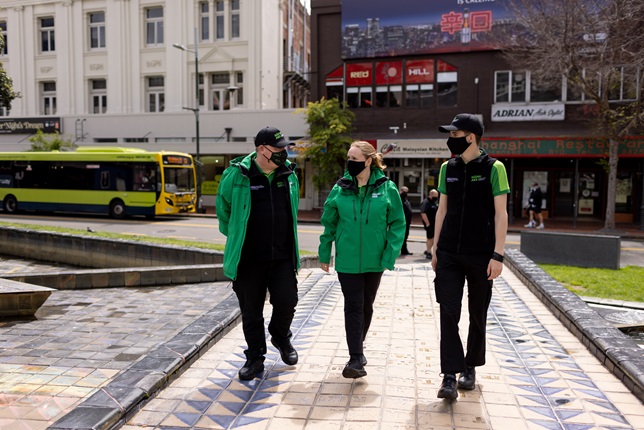 Three people walking across Te Aro park in Wellington.