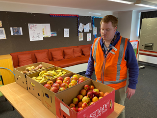A man standing behind a table with fresh produce on top.