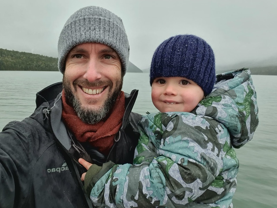 Toby Leggett a year on after recovering from collapsed lung, with dad near lake.