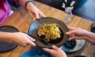 People holding a bowl full of food.