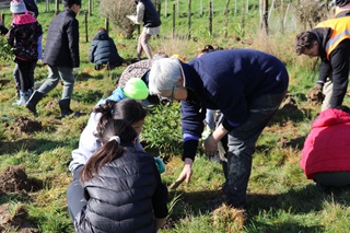 Two kids and a woman planting.