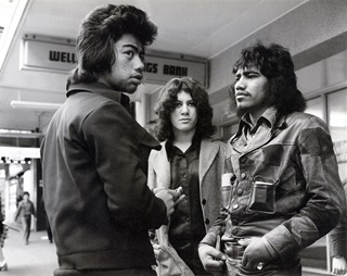 Three people standing on the street.
