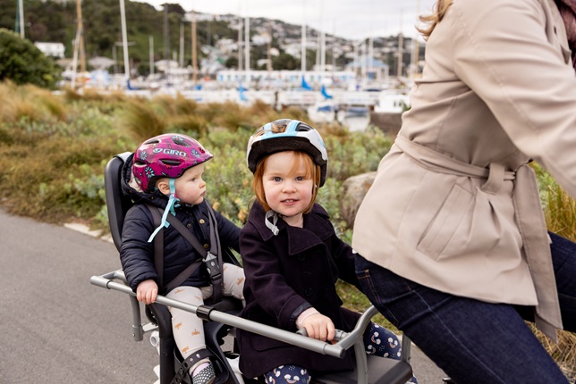 Two kids on the back of a bike.