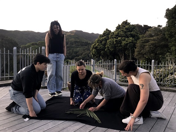A group of people weaving on a deck.