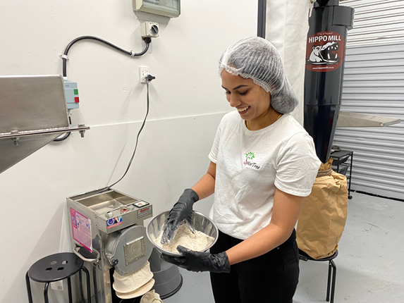 Woman smiling holding a metal bowl of flour.